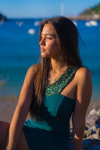 Latin young woman enjoying the summer with a green dress by the sea