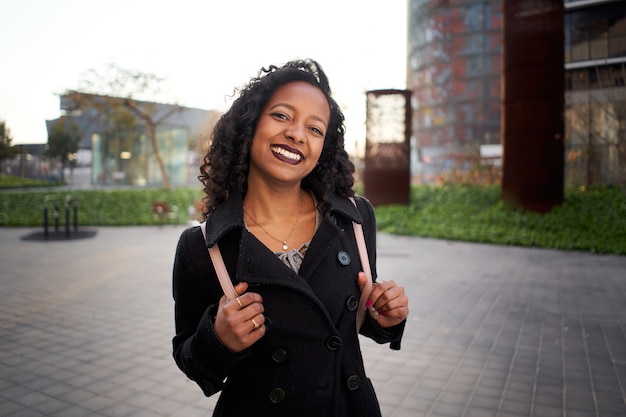 Latina businesswoman smiles happily looking at the camera the young woman is standing next to a mode...