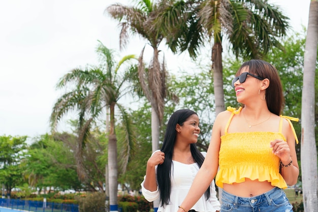 Latina friends feeling good while walking down the street. Urban exterior in summer.