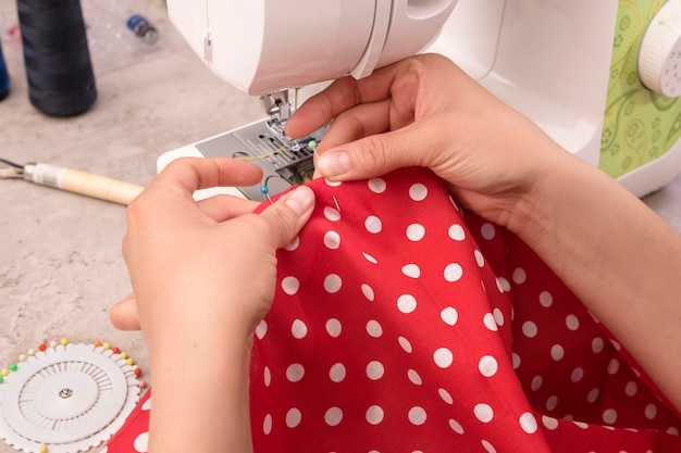 latina woman's hands using sewing machine is sewing a dress