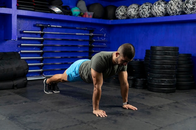 Latino athlete with sportswear in a gym doing high plank