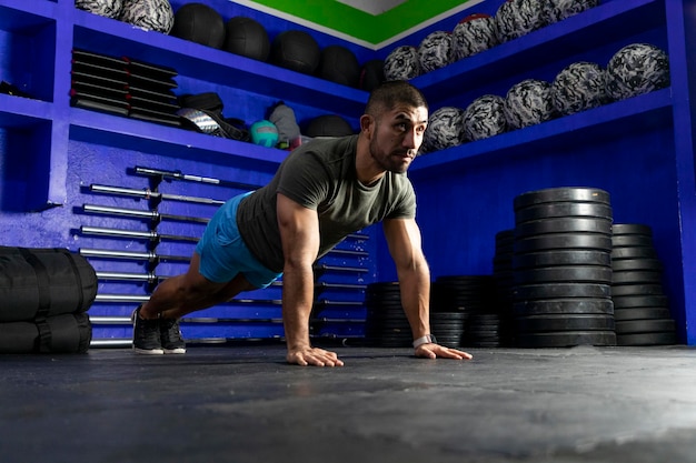 Latino athlete with sportswear in a gym doing high plank