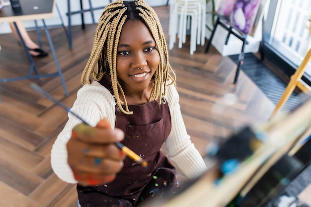 Latino hispanic woman paints on canvas with oil colors in workshop