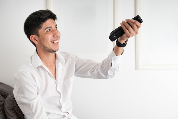 Latino man changing channels with the remote control of the television