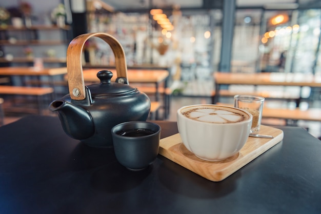 Latte art coffee, cup of hot coffee on wooden tray and dark table