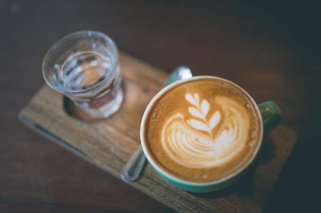 Latte hot coffee with foam milk art on a wooden table