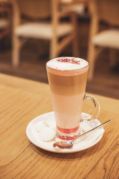 Latte macchiato with cocoa powder and coffee beans on wooden background.latte in glass cup. coffee mocha on the wood desk.Morning with a cup of coffee.retro toning.