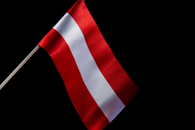 The latvian flag on a black background is developing and flying in the wind