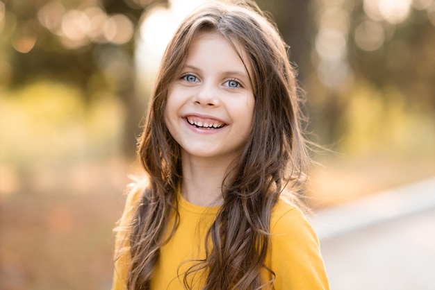 Laughing child girl 5-6 year old with long blonde hair over nature autumn background