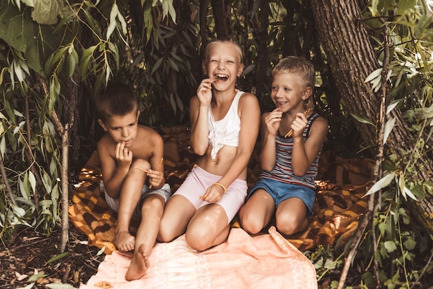 Laughing children play in a hut made of twigs and leaves. Wooden house in the village