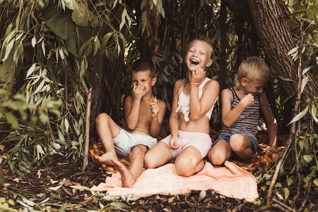 Laughing children play in a hut made of twigs and leaves. Wooden house in the village