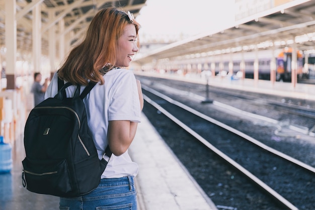 Laughing girl with backpack on railroad