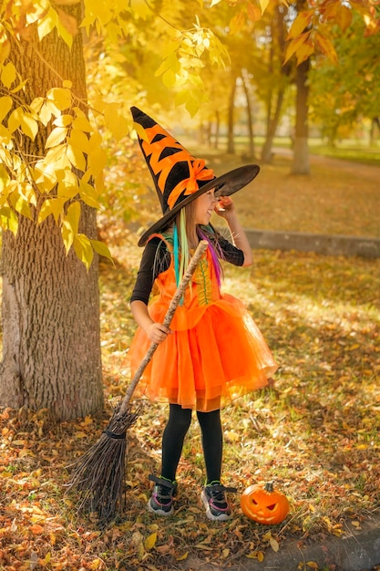 Laughing girl with a broom wearing a hat and dressed