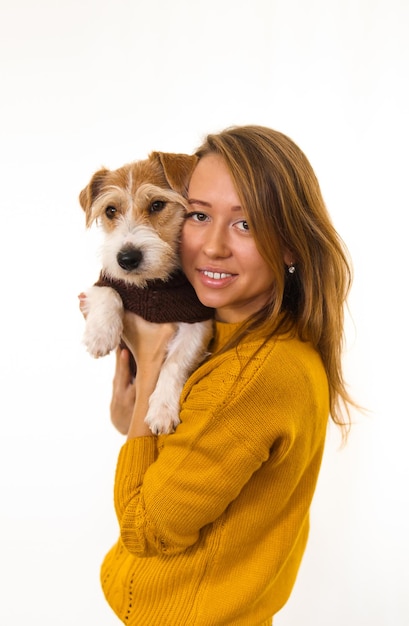 Laughing Girl in a yellow jacket is holding a dog in her arms. Isolate on white background