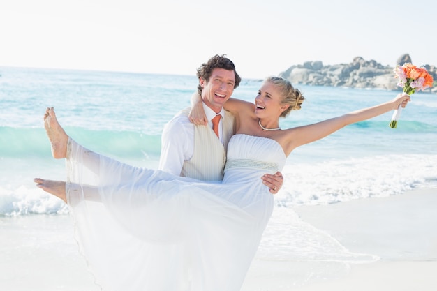 Laughing groom carrying his pretty blonde wife