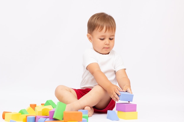 Laughing little boy playing with colorful blocks, isolated on white background