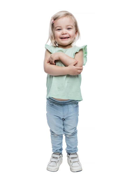 Laughing little girl in jeans and a green blouse Positive and happy childhood Isolated on white background Vertical