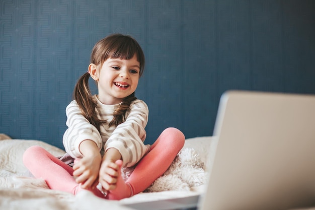 Laughing little girl watching cartoons on a laptop