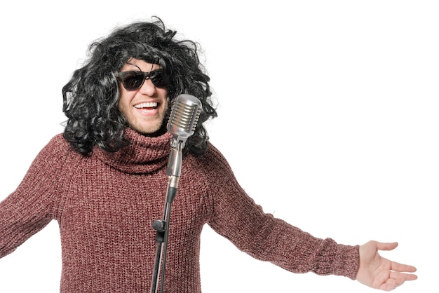 Laughing man in a wig a sweater and sunglasses at the microphone Isolated