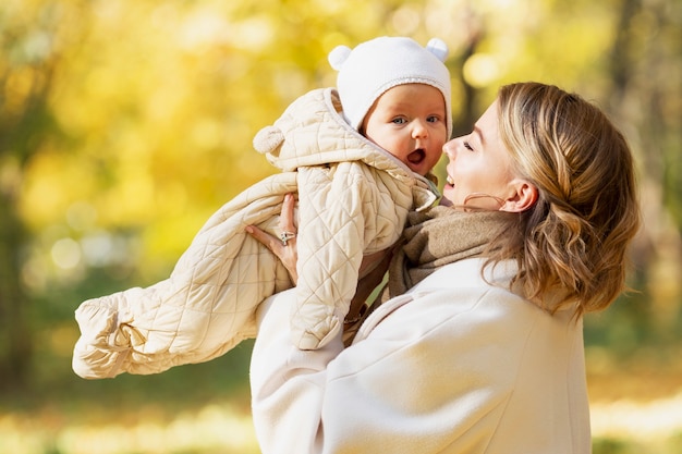 Laughing mom with her baby in an autumn park on a sunny day. Close-up. Love and tenderness.