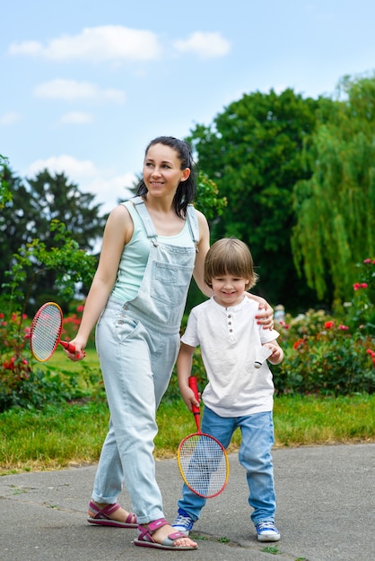 Laughing mum rolls on a back of the small son in park