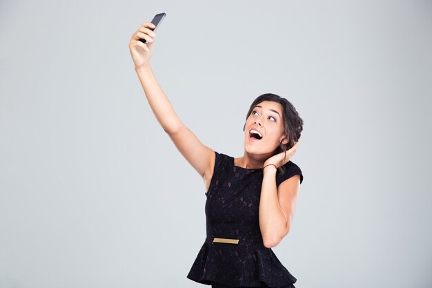 Laughing woman in black dress making selfie photo