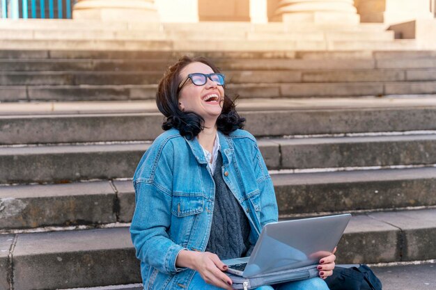 Laughing woman student e learning distance training course study working on stairs