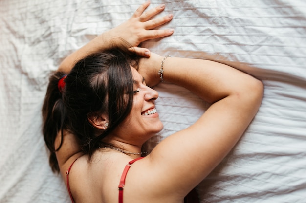 Laughing woman tries to fall asleep lying down on the bed.