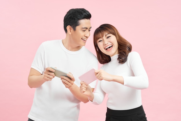 Laughing young couple friends guy girl in white t-shirts posing isolated on pink  background.