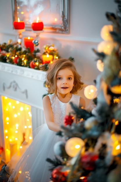 Laughinhg child peeping from behind Christmas tree