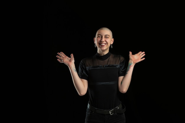 Laughting, cute. Monochrome portrait of young caucasian bald woman isolated on black wall.