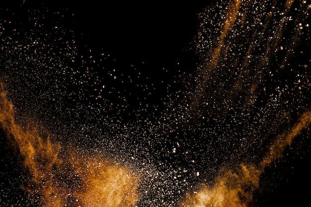 Launched orange color powder explosion on black background. 