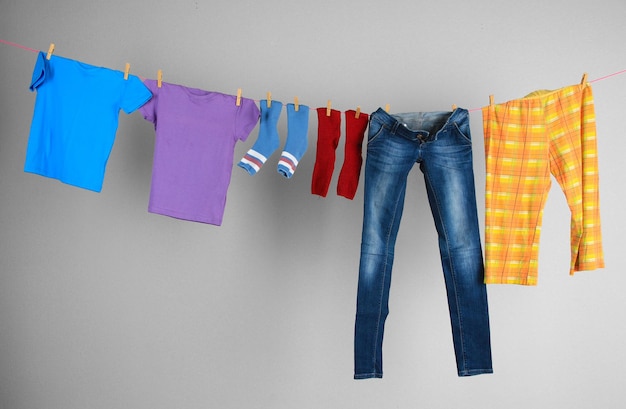 Laundry line with clothes on wall background