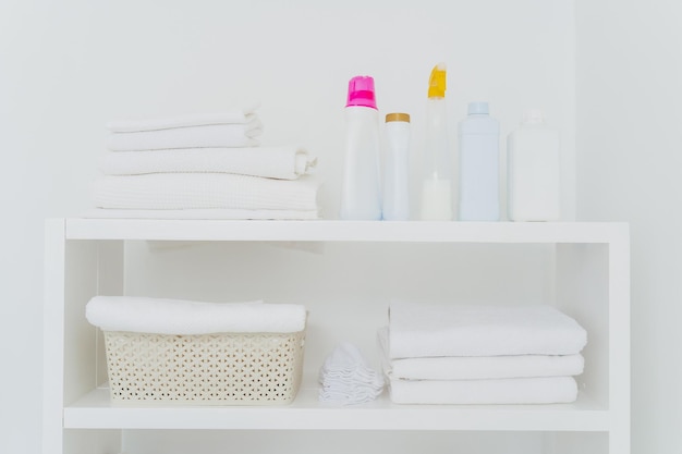 Laundry room with neatly folded towels bottles of liquid washing or detergents Everything in white colors Daily chores and laundry day