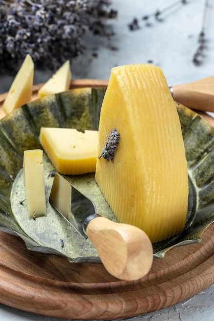 Lavender cheese with dry lavender flowers on tray. Lavender cheddar cheese slices