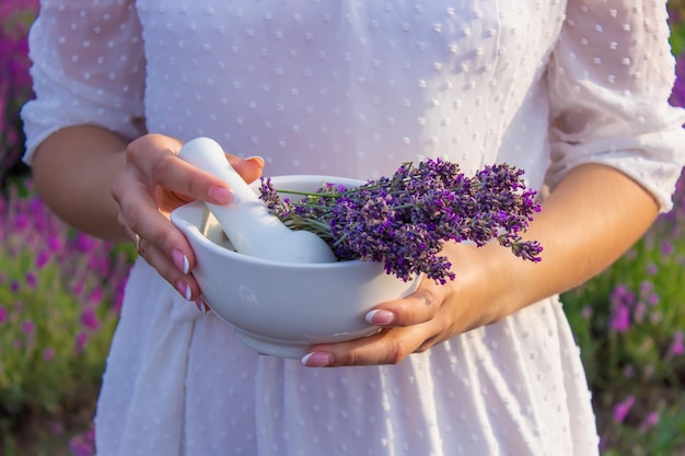 Lavender Essential oil bottle on wood table and flowers field background