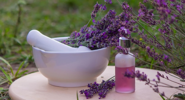 Lavender Essential oil bottle on wood table and flowers field background