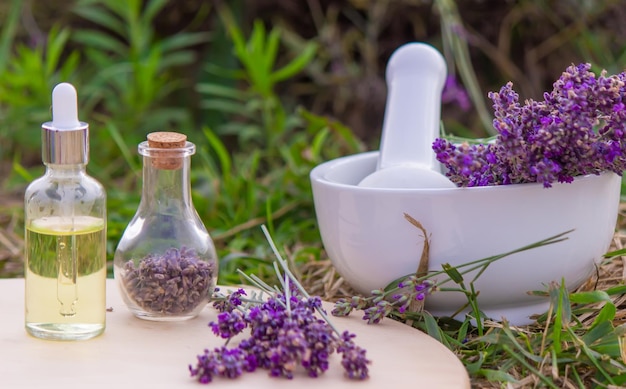 Lavender Essential oil bottle on wood table and flowers field background