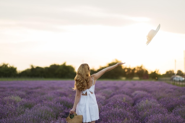 Lavender field sexy girl portrait in straw hat Provence France A girl in white dress walking through lavender fields at sunset