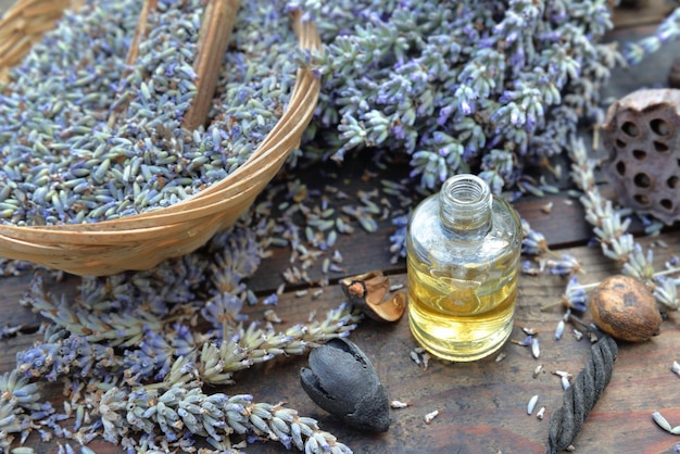 Lavender flowers petals from garden in a little basket with essential oil bottle on a wooden tablex9