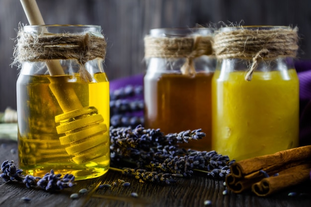 Lavender and herbal honey in glass jars on dark wooden table.