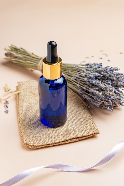 Lavender oil or serum and lavender flowers on beige backgrund Skincare cosmetics products Set natural spa beauty products Lavender essential oil serum massage oil liquid Mockup