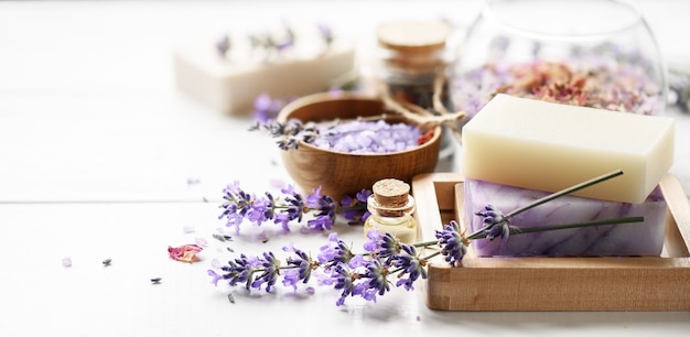 Lavender Spa products and lavender flowers on a white table. Handmade soap on wooden soap dish, essential oil and lavender bath salt - beauty treatment.