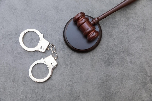 Law theme court of law trial in session judge gavel handcuffs on grey table in lawyer office or cour