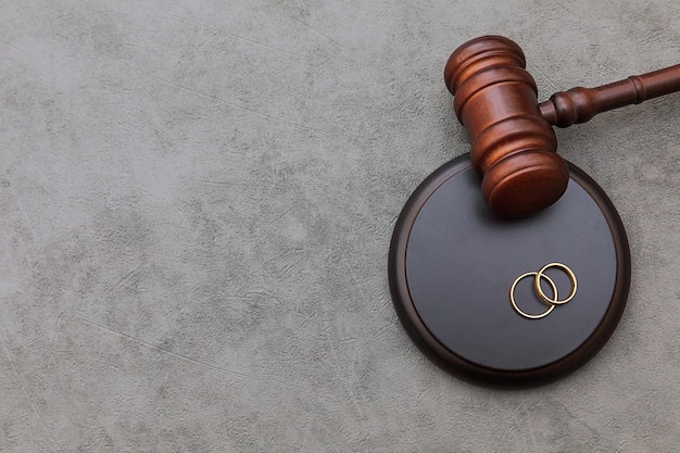 Law theme Judge gavel wedding rings on concrete stone grey background Divorce proceedings Mallet of judge deciding on marriage divorce marital agreement legalities of divorce