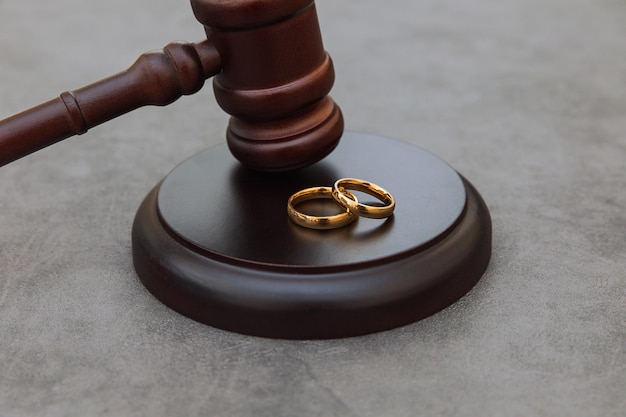 Law theme judge gavel wedding rings on concrete stone grey background divorce proceedings mallet of