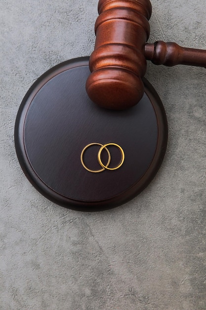 Law theme judge gavel wedding rings on concrete stone grey background divorce proceedings mallet of