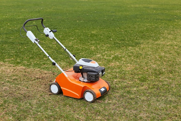 Lawn mover on green grass on surface of field or garden