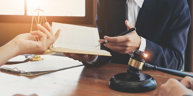 Lawyer hands holding a legal book and clarify the law to client while sign a contract at lawyer office