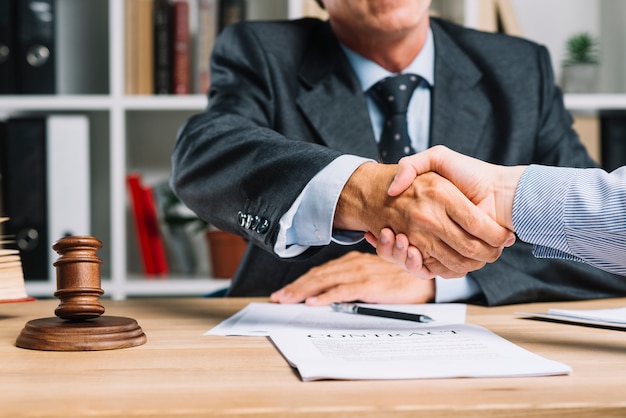 Lawyer and his client shaking hands together over the desk